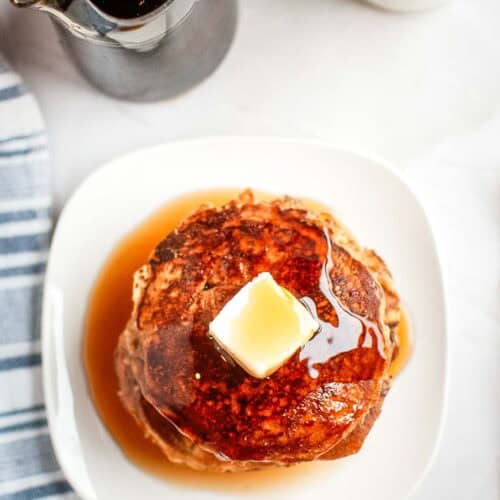 Top-down shot of Buttermilk Oatmeal Pancakes on a white plate.