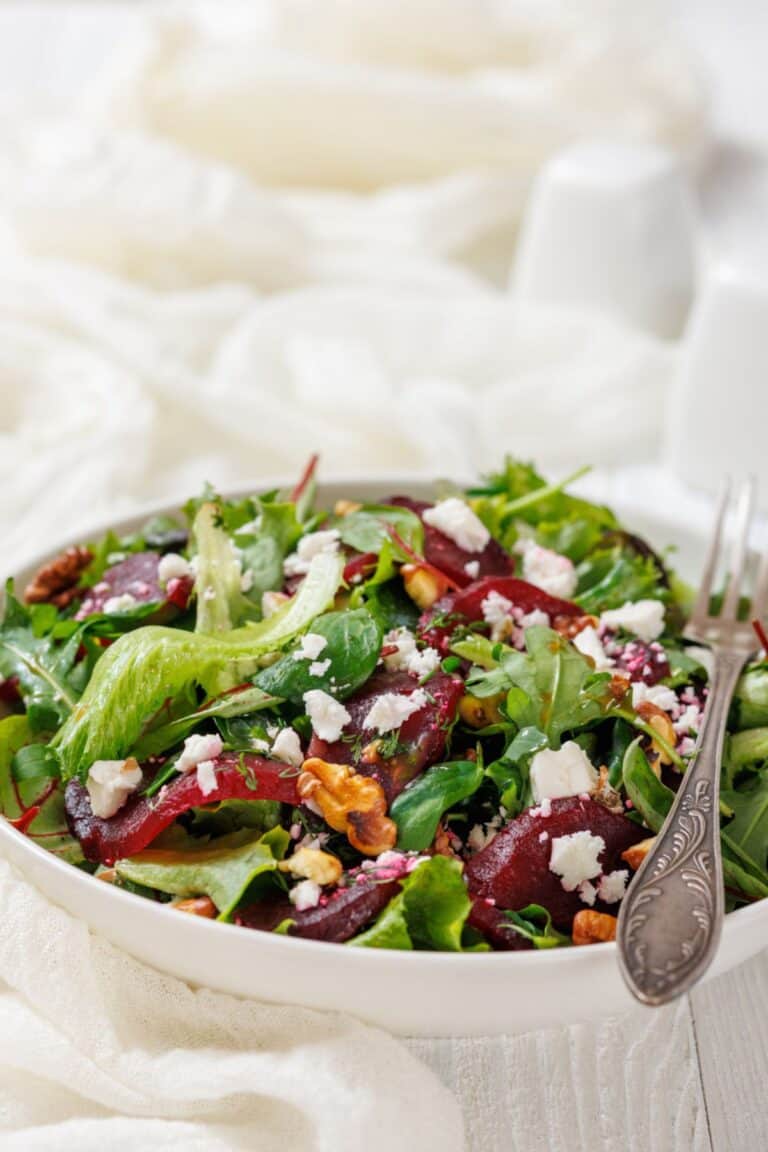 Beet Salad with Goat Cheese and Walnuts on a white bowl with a fork.