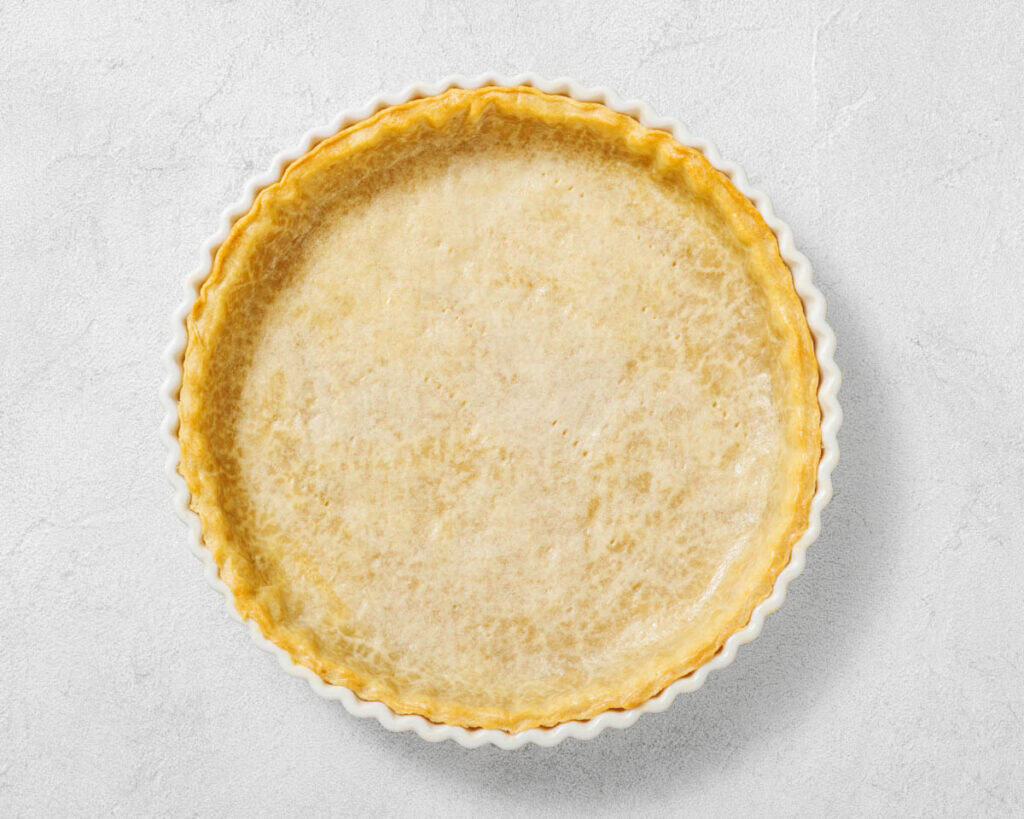 Overhead shot of a baked pie crust in a white fluted pie dish.