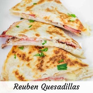 Three slices of quesadilla filled with meat and cheese, garnished with chopped herbs, on a white plate. Text at the bottom reads "Reuben Quesadillas.