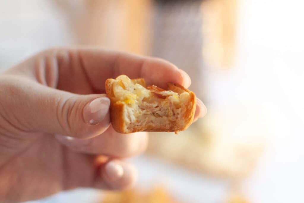 A hand holds a partially eaten Ham & Cheese Puff, revealing layers of pastry, ham, and cheese.