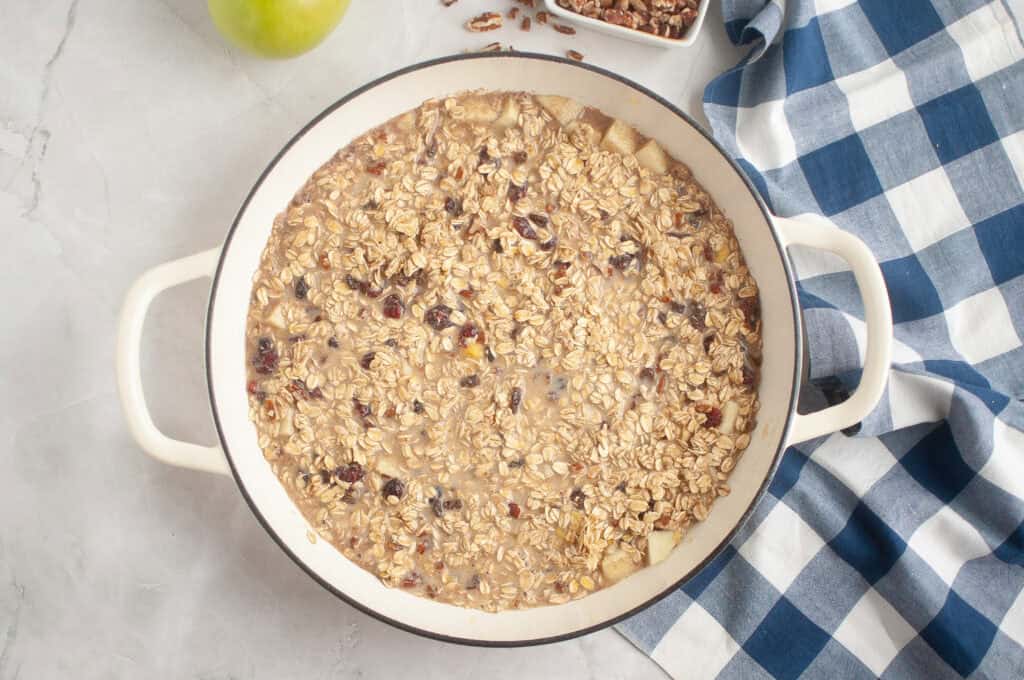 Overhead shot of oatmeal batter with chopped apples and cranberries in a white baking dish, ready to be baked.