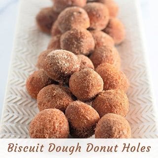 A rectangular white platter holds a pile of sugar-coated biscuit dough donut holes. Text at the bottom reads "Biscuit Dough Donut Holes.