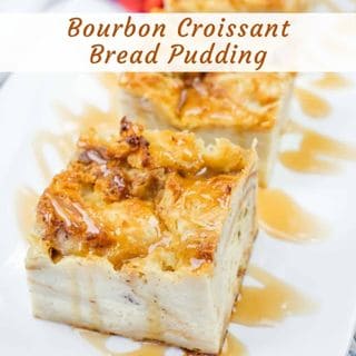 Two square slices of bourbon croissant bread pudding are drizzled with caramel sauce on a white plate.