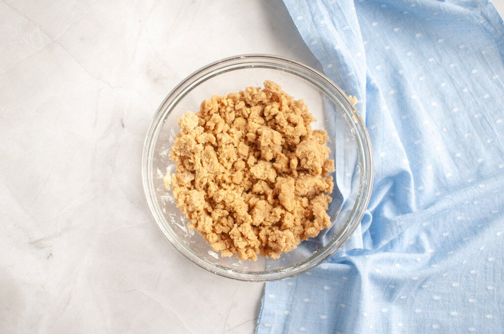 Overhead shot of a light brown, crumbly mixture in a glass bowl.