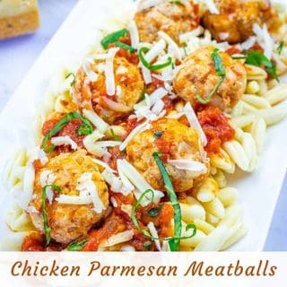 A plate of pasta topped with tomato sauce, chicken parmesan meatballs, shredded cheese, and fresh basil.