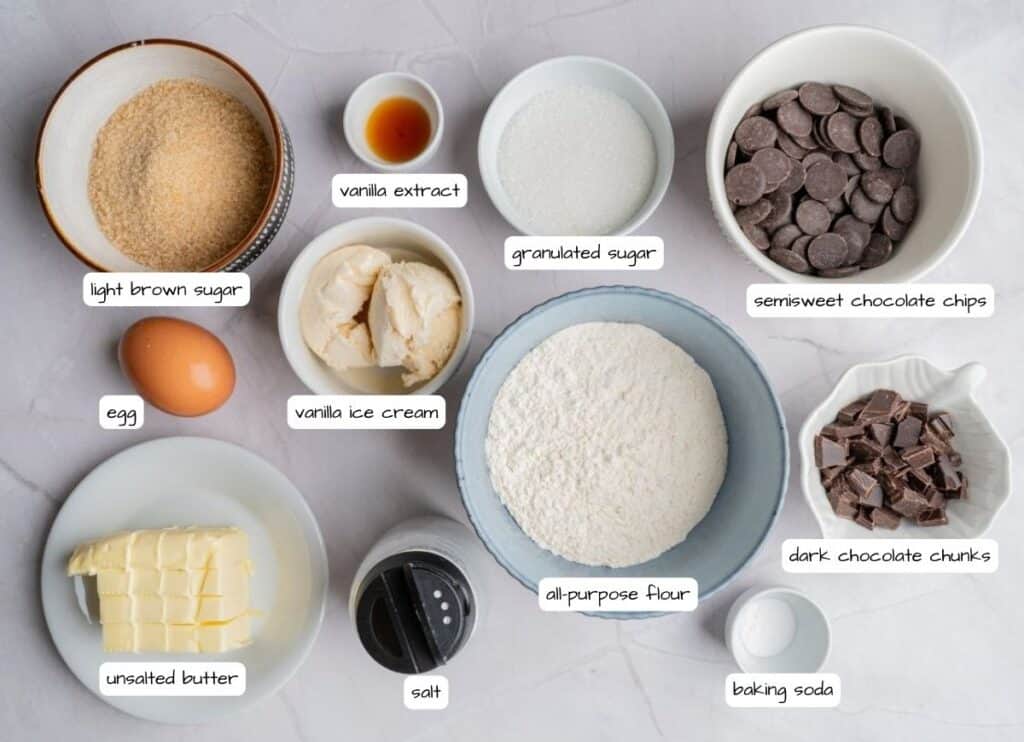 Overhead shot of labeled ingredients for a chocolate chip skillet cookie, including flour, sugars, butter, egg, vanilla, ice cream, baking soda, salt, and chocolate.