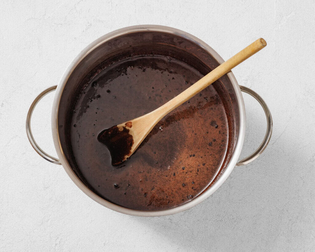 Image of a mixture, combination of sugar, milk, butter, and cocoa powder in a medium saucepan.