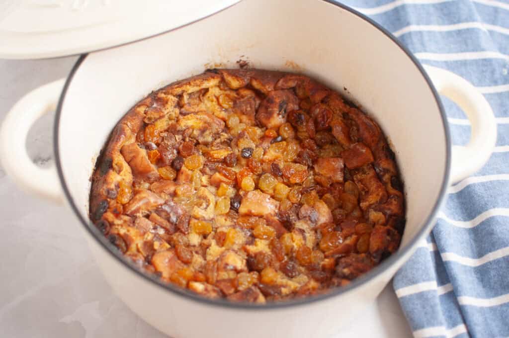 Overhead shot of a baked Cinnamon Roll Casserole with visible apples and raisins in a white pot.