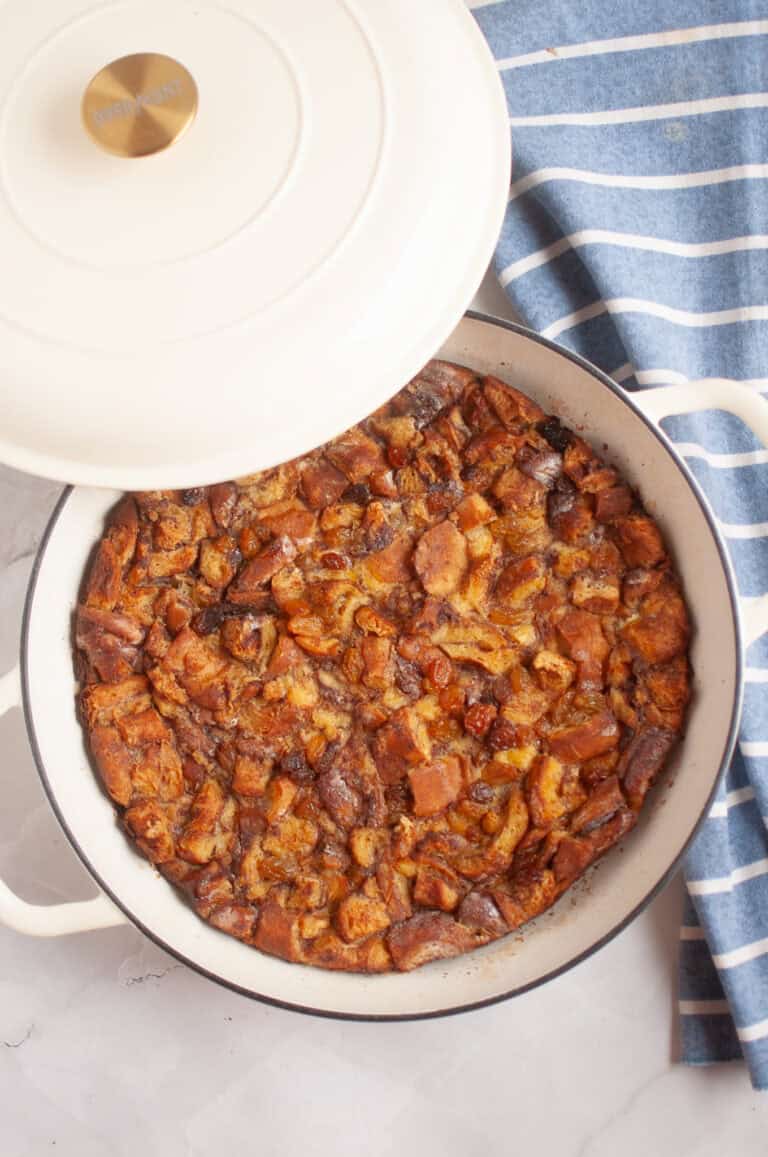 Overhead shot of a freshly baked Cinnamon Roll Casserole in a white pot with the lid partially removed.