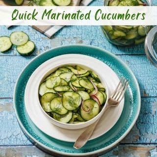A bowl of marinated cucumber salad with dill and red onion sits on a blue plate, with a fork beside it and a jar of cucumbers in the background. Text reads "Quick Marinated Cucumbers.