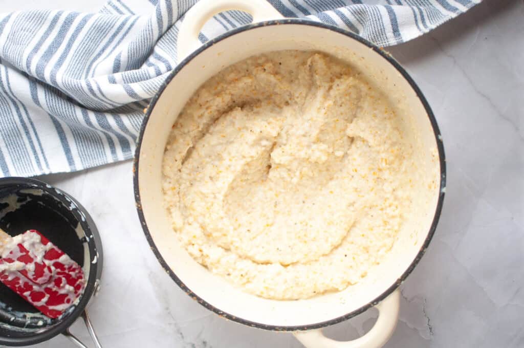 Overhead shot of a white pot containing creamy, off-white corn grits.