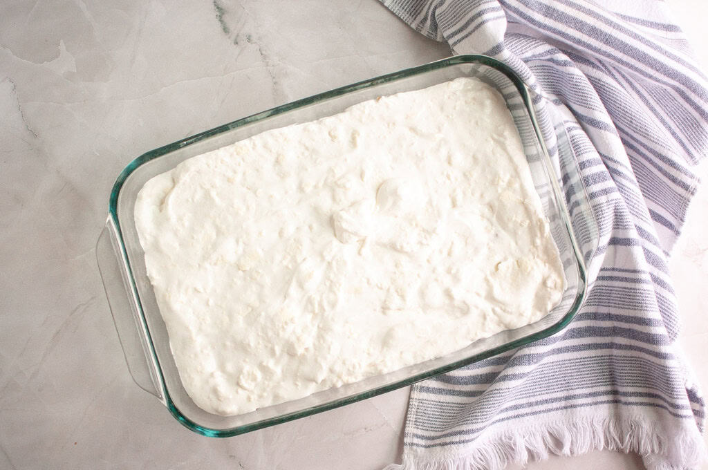 Spreading the cream cheese mixture over the cooled pretzel crust.