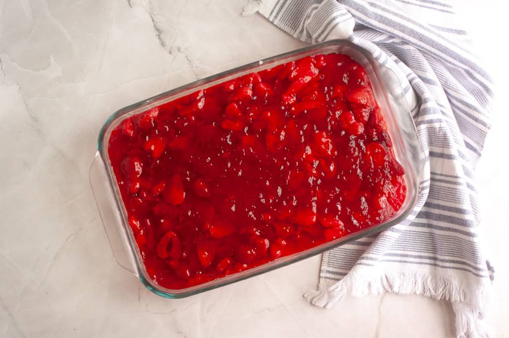 Gently spooning it over the chilled cream cheese layer, spreading it out evenly.