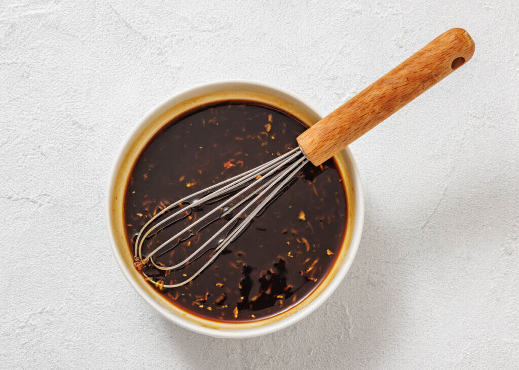 A whisk in a bowl of sauce.
