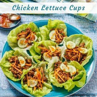 A plate of chicken lettuce cups filled with ground chicken, shredded carrots, and cucumber slices, arranged on a blue plate.