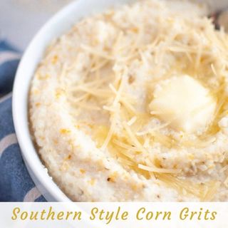 A bowl of creamy southern-style corn grits topped with shredded cheese and a pat of melting butter.