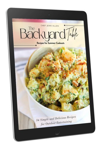 A digital tablet displays the cover of a cookbook titled "The Backyard Table" featuring a bowl of potato salad and text about summer cookout recipes by Chef Jenn Allen.