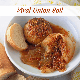 A bowl with a seasoned, boiled onion cut open, served with sauce and slices of bread on the side. The text "Viral Onion Boil" appears at the top.