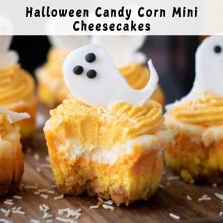 Mini cheesecakes decorated with orange and white frosting, topped with ghost-shaped candies and chocolate dots, with one cheesecake partially eaten.