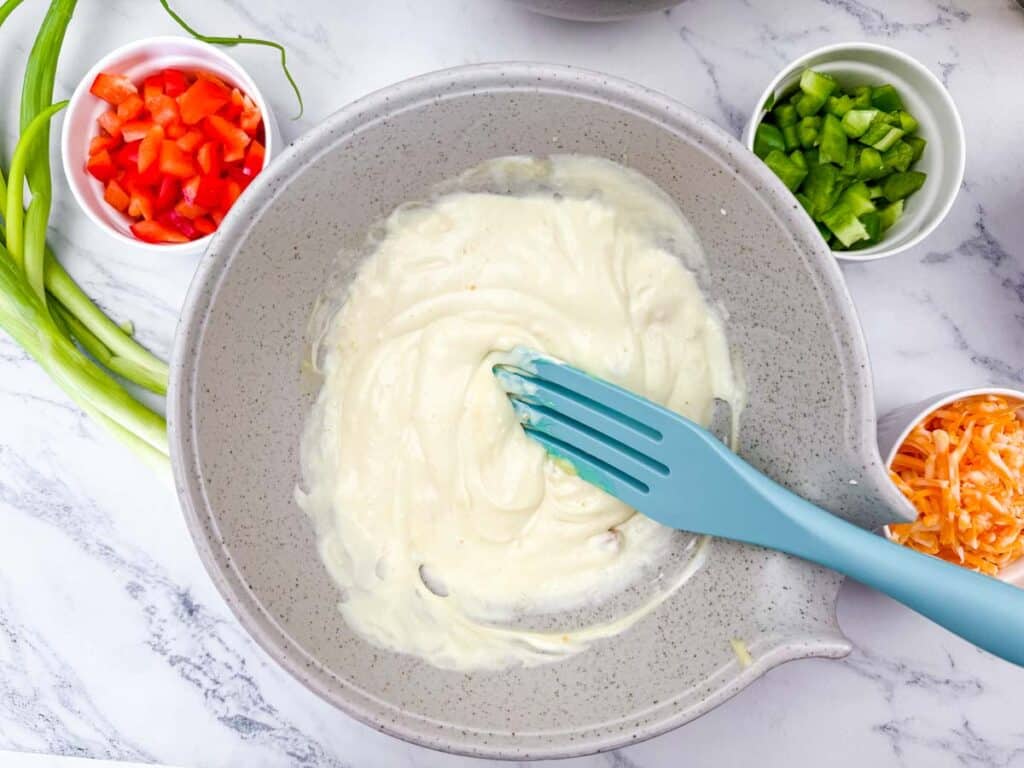 A bowl of chicken salad with a blue spoon.