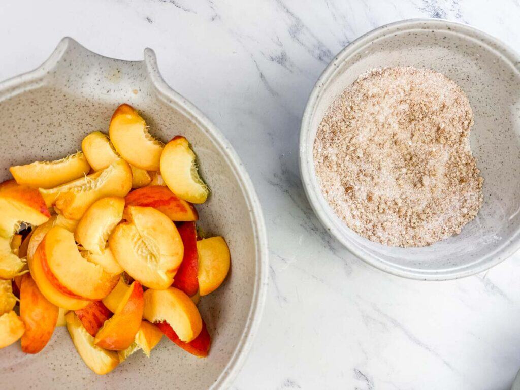 Bowls with pears and other bowl with mixed dry ingredients for Peach Cobbler.