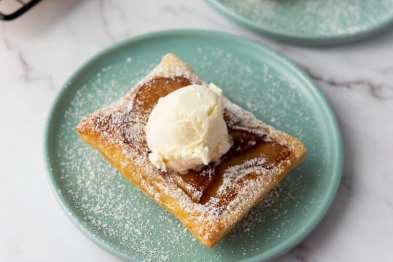 Golden brown Belgian waffle topped with vanilla ice cream on a mint green plate, dusted with powdered sugar.