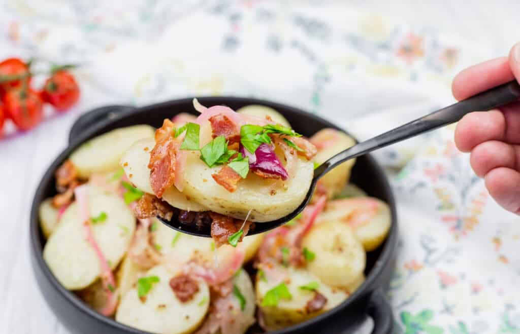 A spoonful of potato salad in a bowl.