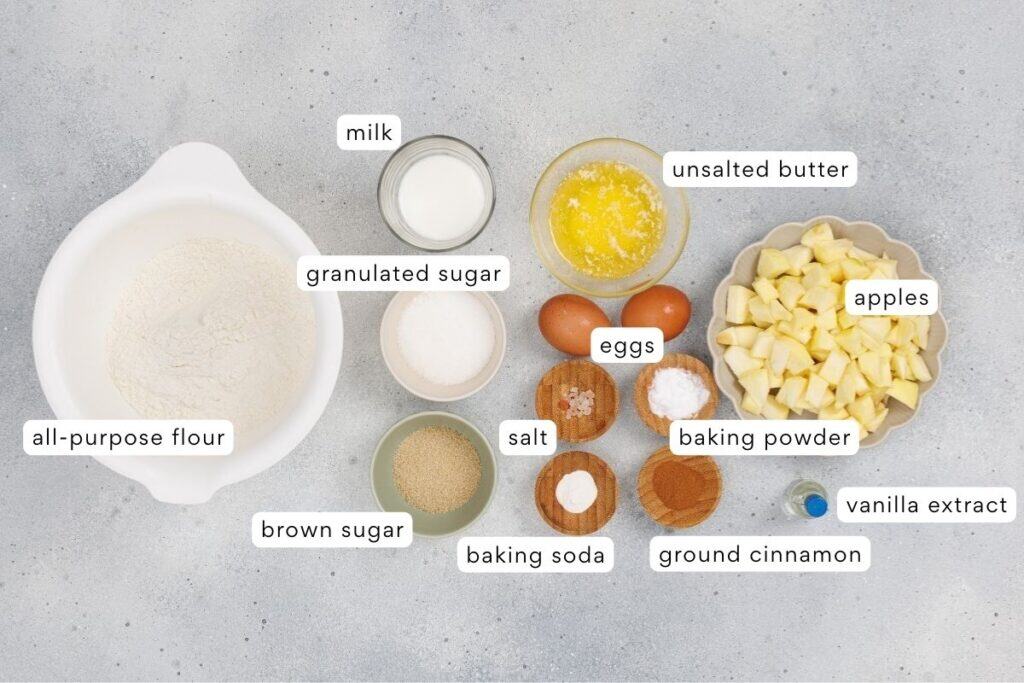 Flour, eggs, apples, and baking ingredients for baking recipes on gray surface.