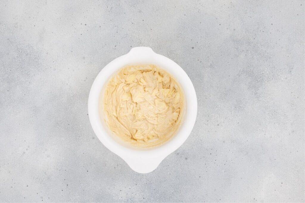 Softened butter in a white bowl on a gray background.