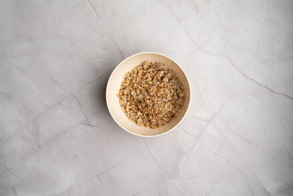 Crunchy mixed toppings in a white bowl on a marble surface.