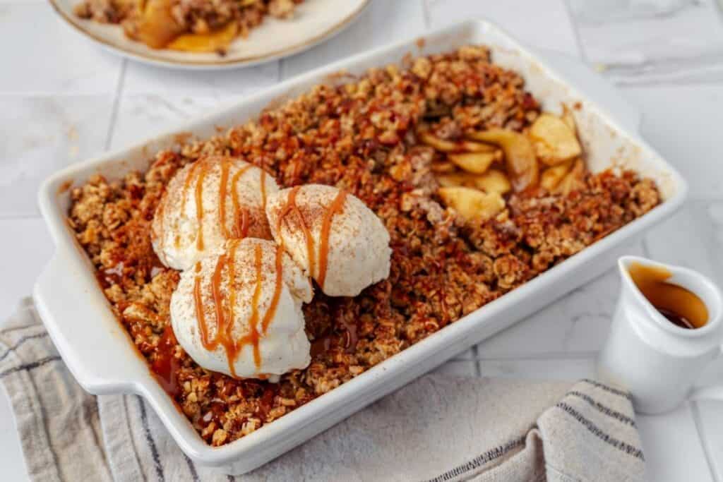Creamy apple crumble dessert with vanilla ice cream and caramel sauce. Perfect for comfort food and family gatherings.