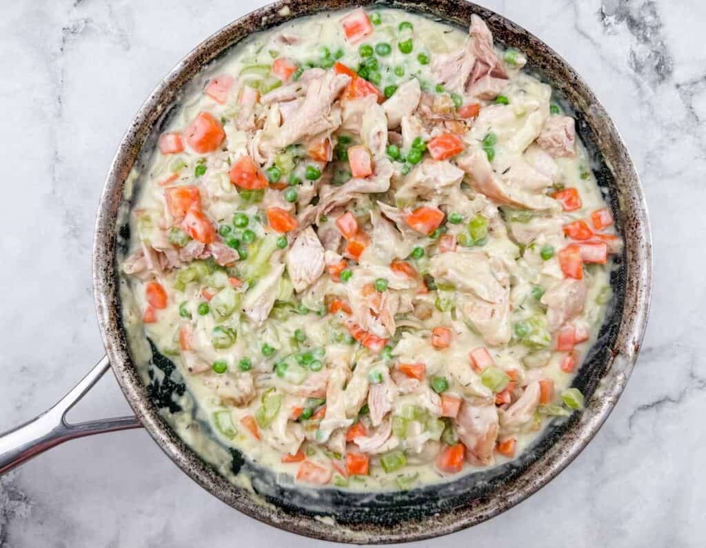 Creamy chicken and vegetable skillet with tender chicken, peas, carrots, and celery in a rich sauce. Perfect for hearty, satisfying meals.