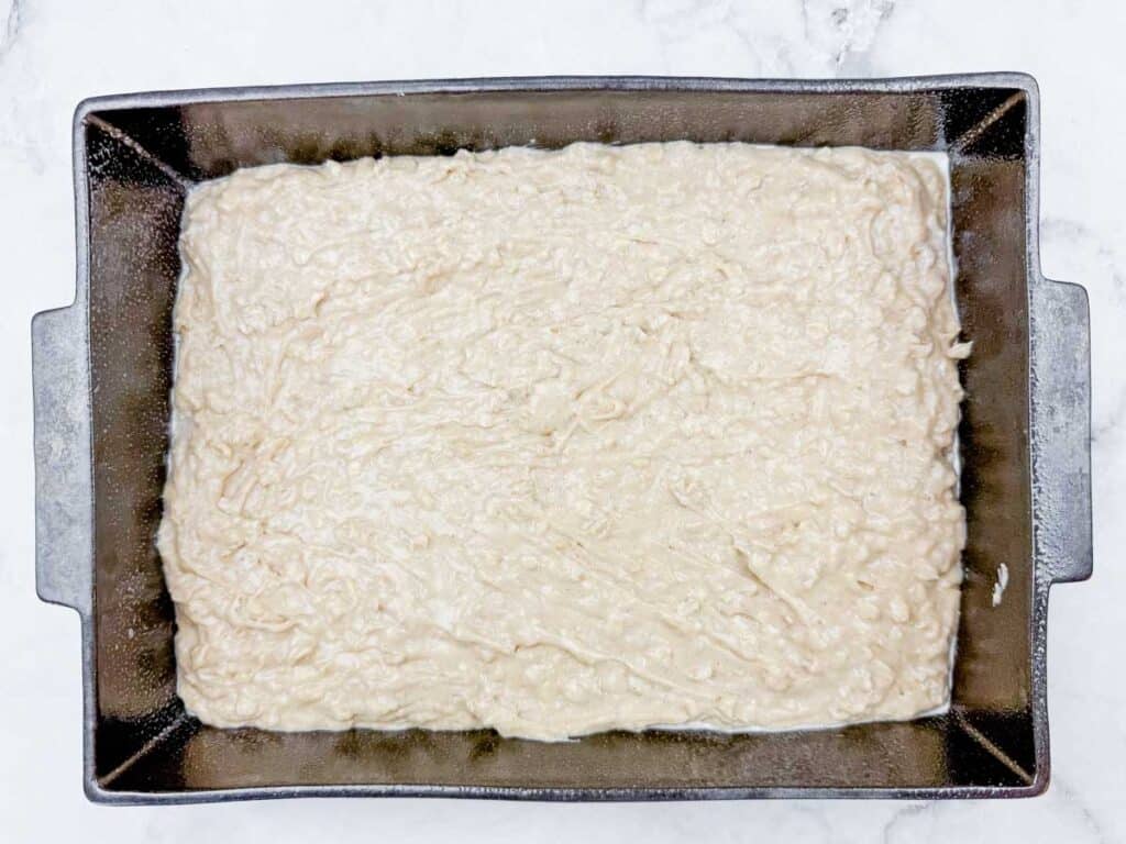 Cake batter spread evenly in a baking pan, ready for baking or chilling. 