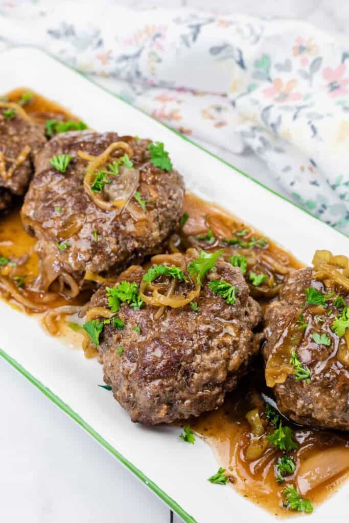 Pieces of Mississippi Salisbury Steak topped with parsley on a white platter.