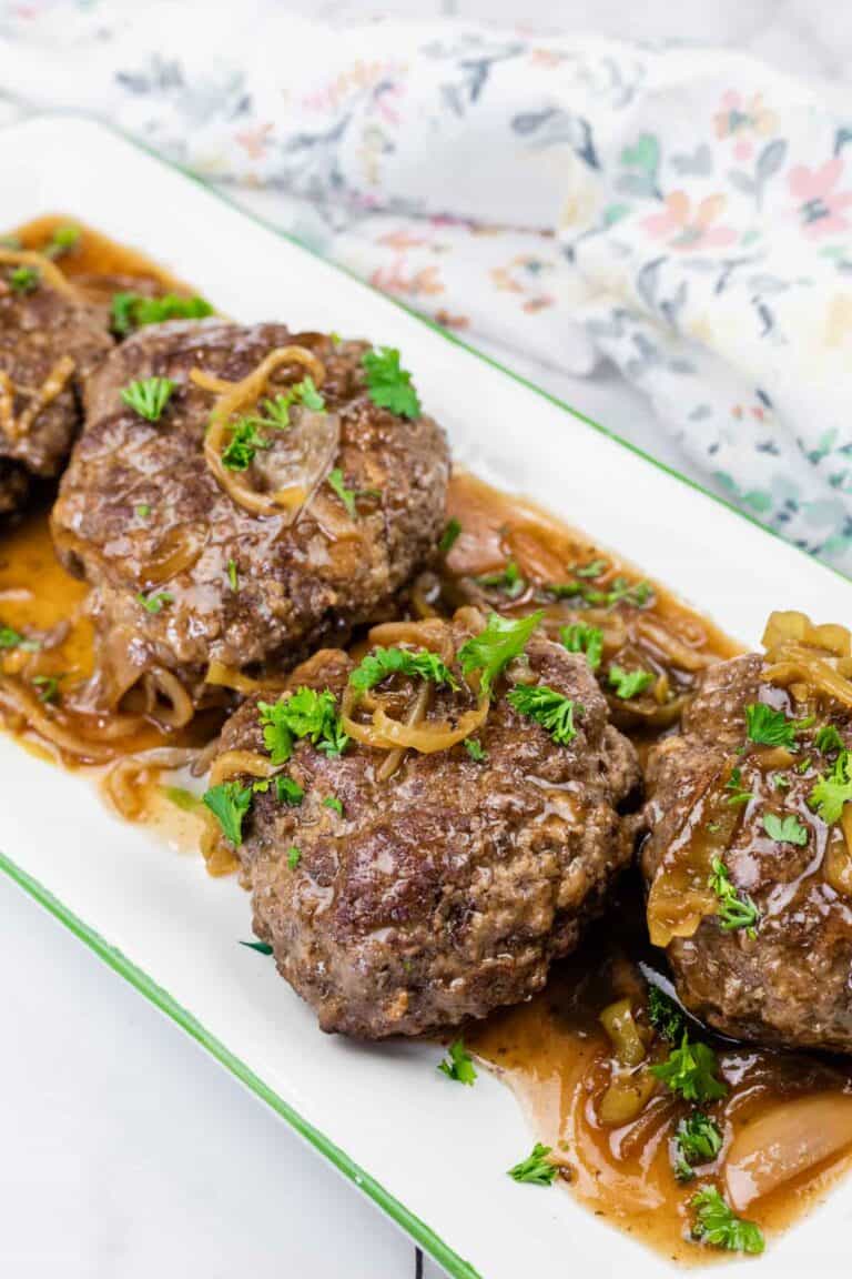 Pieces of Mississippi Salisbury Steak topped with parsley on a white platter.