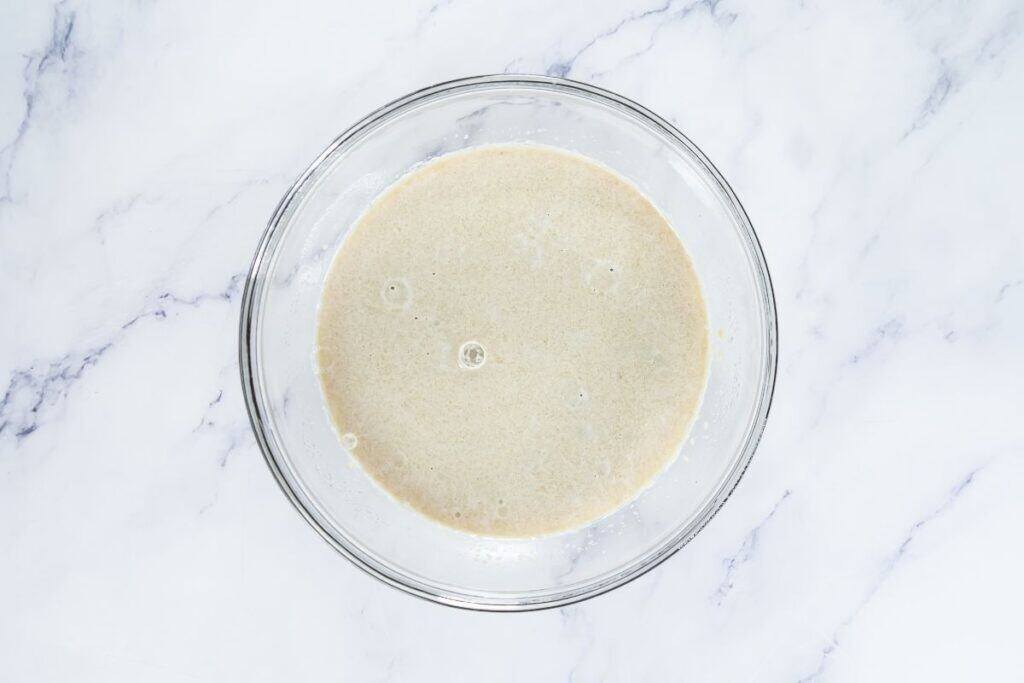 Creamy batter mixture in a clear glass bowl on marble surface.