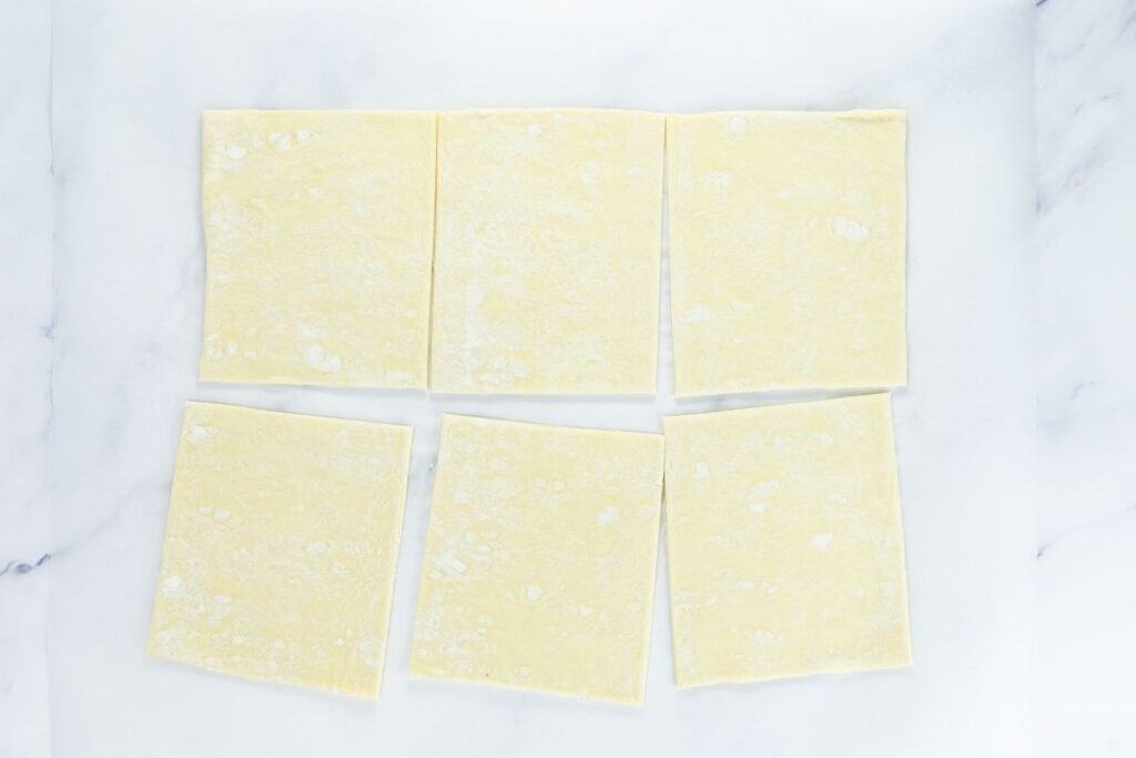Plain puff pastry squares laid out on parchment paper.