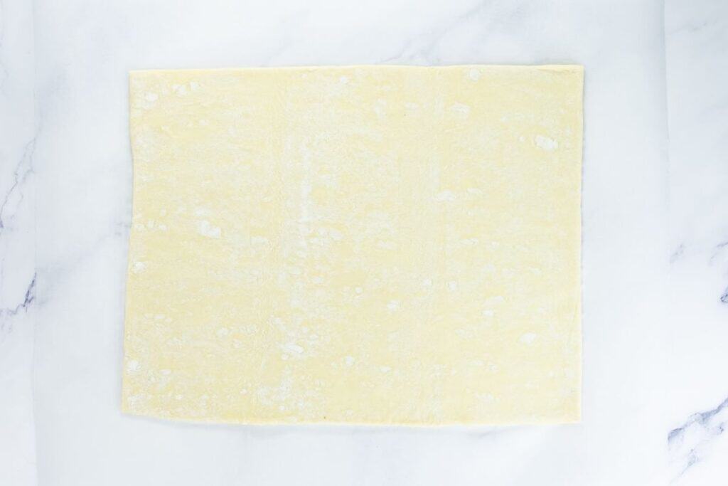 Full sheet of puff pastry rolled out on parchment paper.