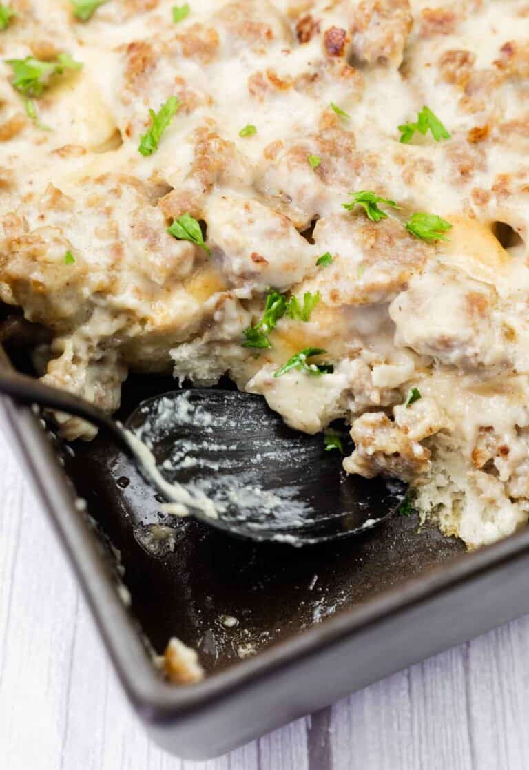 A baking dish with a creamy casserole topped with ground meat and chopped parsley.