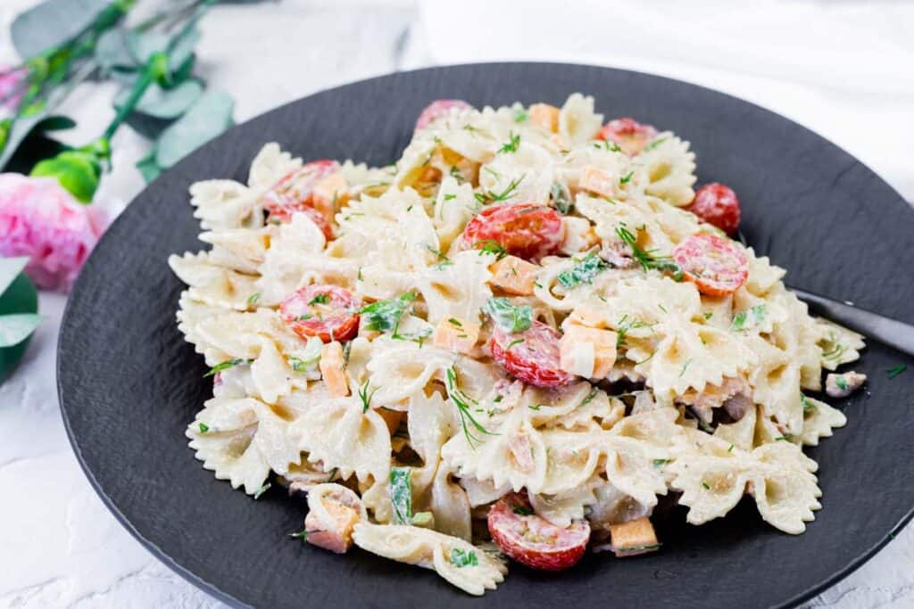 Classic Bacon Pasta Salad on a black plate with serving spoon.