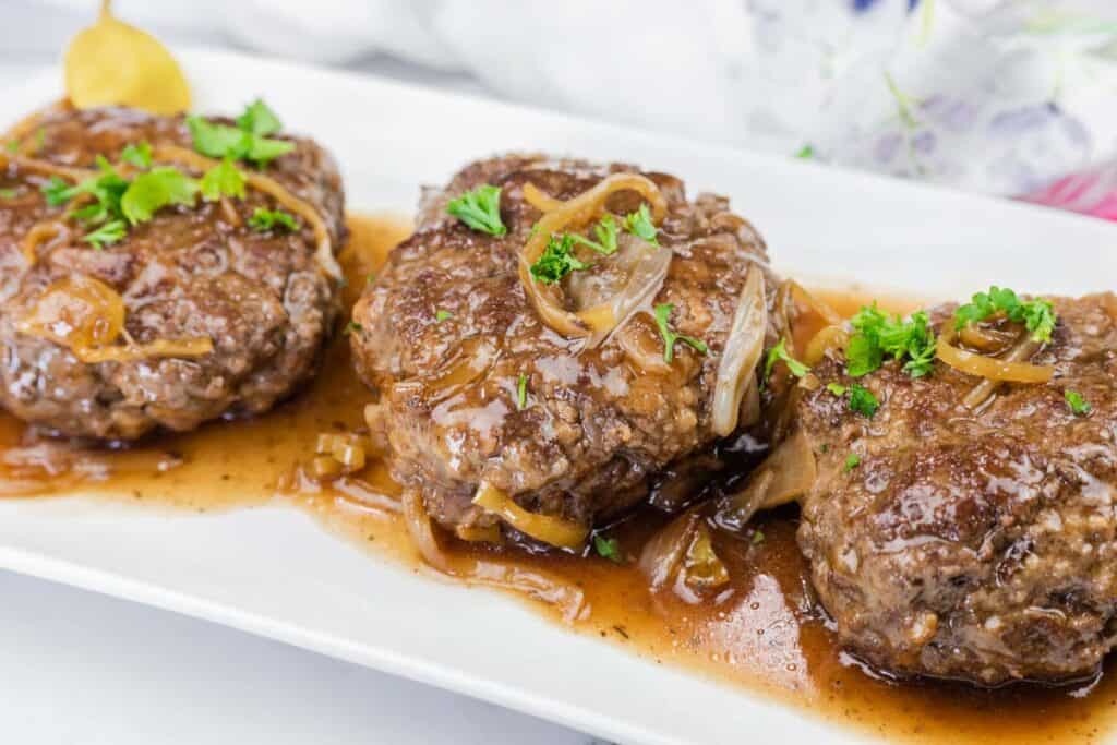 A close-up shot of Mississippi Salisbury Steak on a white platter.
