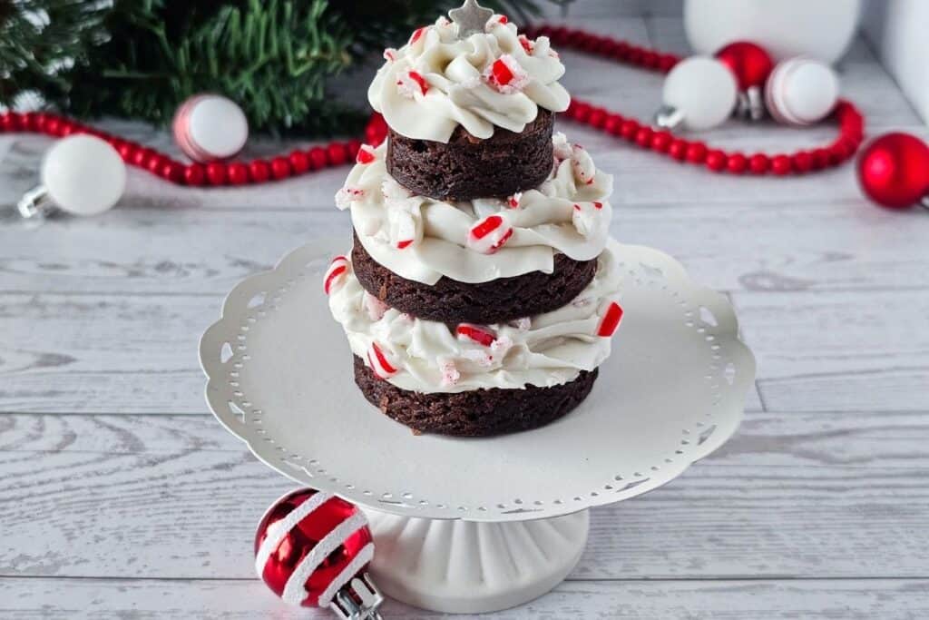Chocolate peppermint cupcakes with white frosting and peppermint sprinkles on a decorative cake stand, holiday Christmas dessert.