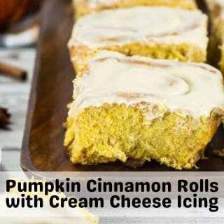 A square of golden Pumpkin Cinnamon Rolls with Cream Cheese Icing plated on a wooden tray.