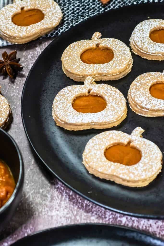 Pumpkin Linzer Cookies on a black plate.