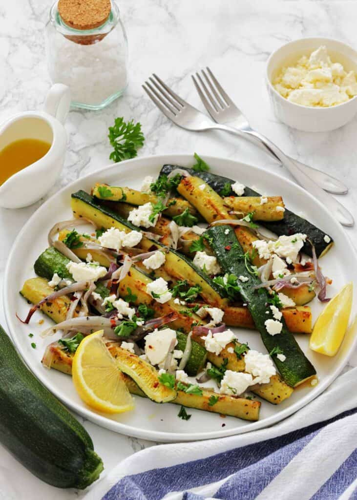 Fresh zucchini sticks seasoned with herbs in a stainless steel bowl for healthy snacks.