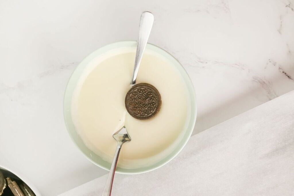 Spoon to lower each Oreo cookie into the melted almond bark.