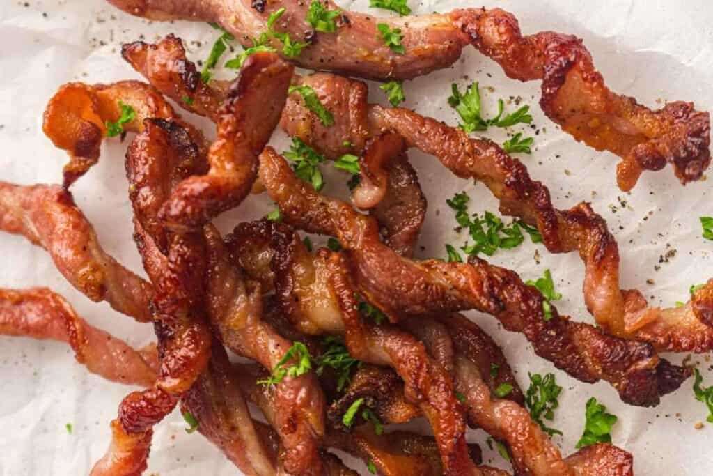 Crunchy twisted bacon garnished with crisp green leaves, adding freshness to every bite.