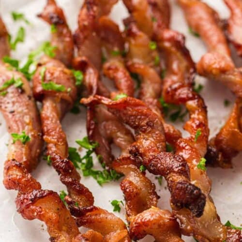 Crunchy twisted bacon garnished with crisp green leaves, adding freshness to every bite.