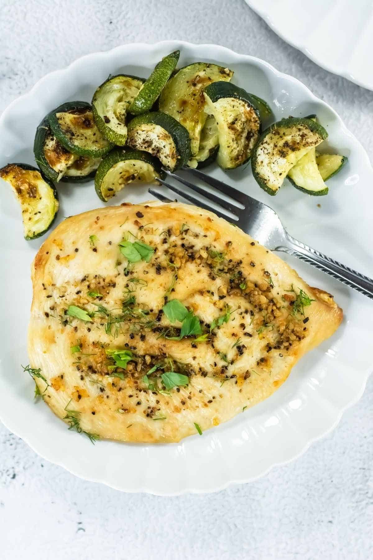 Healthy grilled chicken served with roasted zucchini and green peppers, seasoned with herbs and spices.